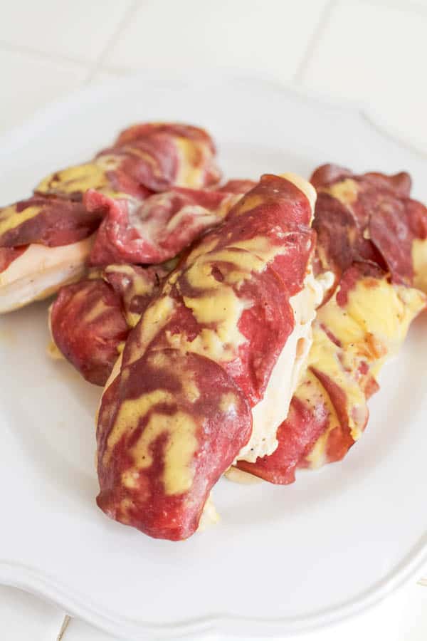 Baked chicken breasts topped with dried beef slices on a plate. 