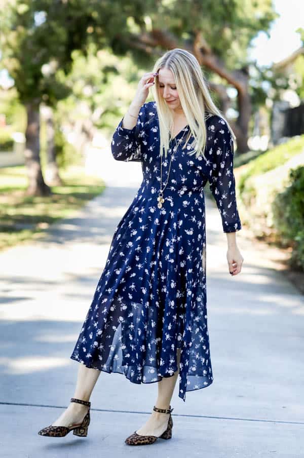Blonde woman in a blue floral dress outside. 
