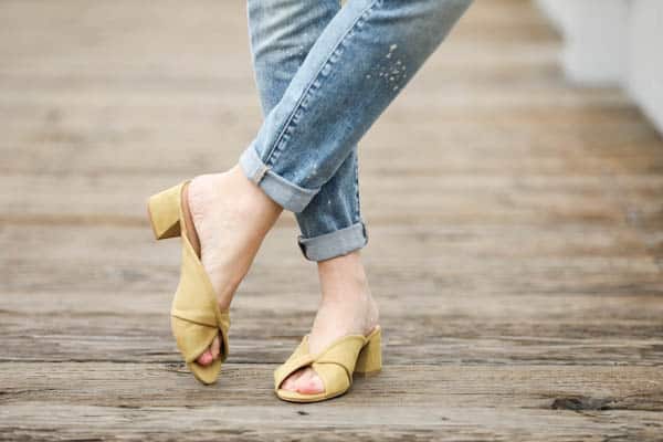 Close up on block heeled mules in lime green on a woman's wearing jeans. 