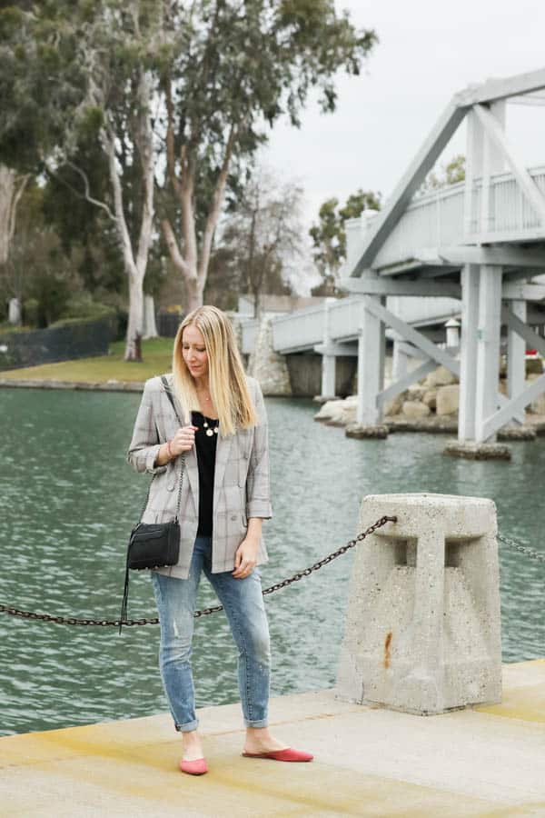 Woman in a blazer and jeans by a lake. 