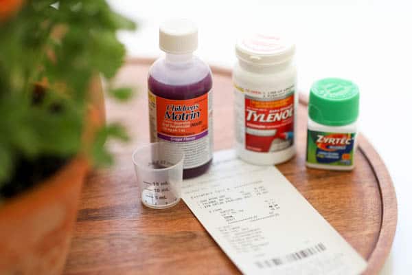 A tray on a table with bottles of over the counter medicine and a receipt. 