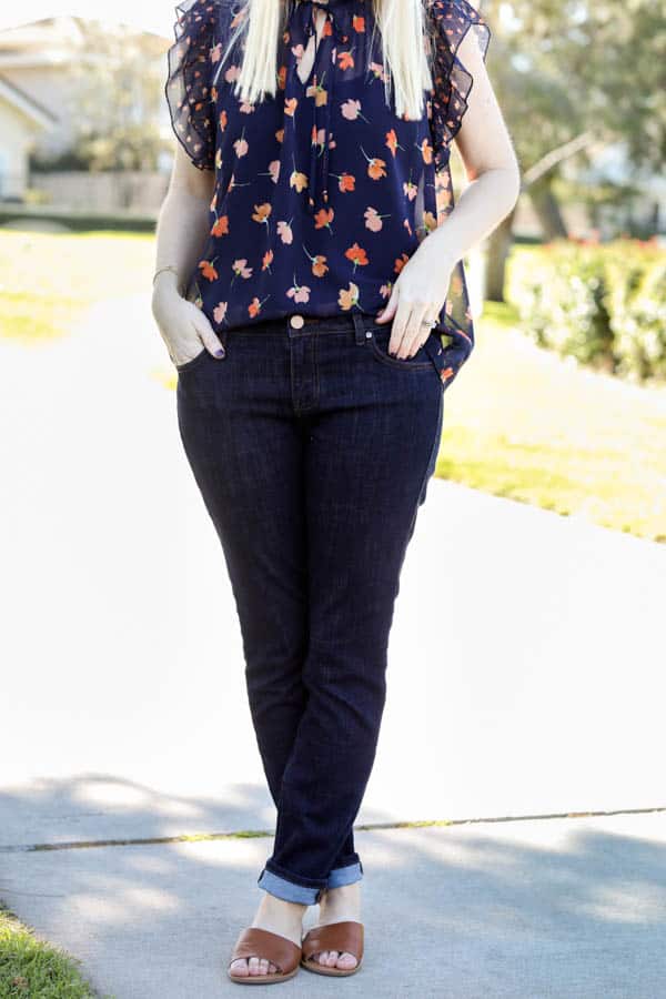 Woman in dark jeans with a blue ruffle sleeve floral blouse. 