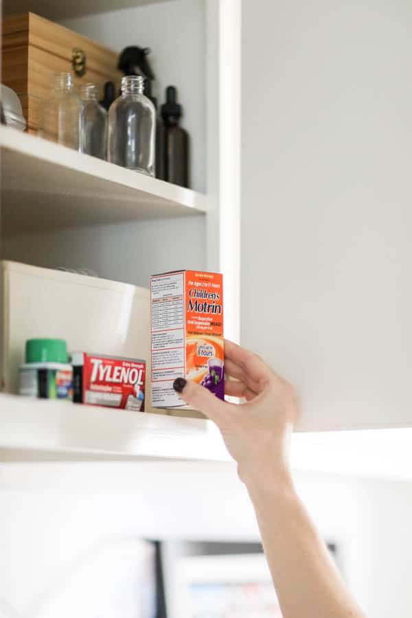 Woman's hand taking a box of Children's Motrin out of the cupboard.