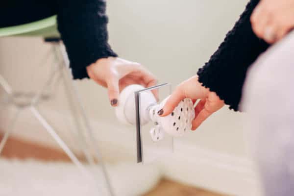 Woman plugging in a wall aromatherapy diffuser to an outlet. 
