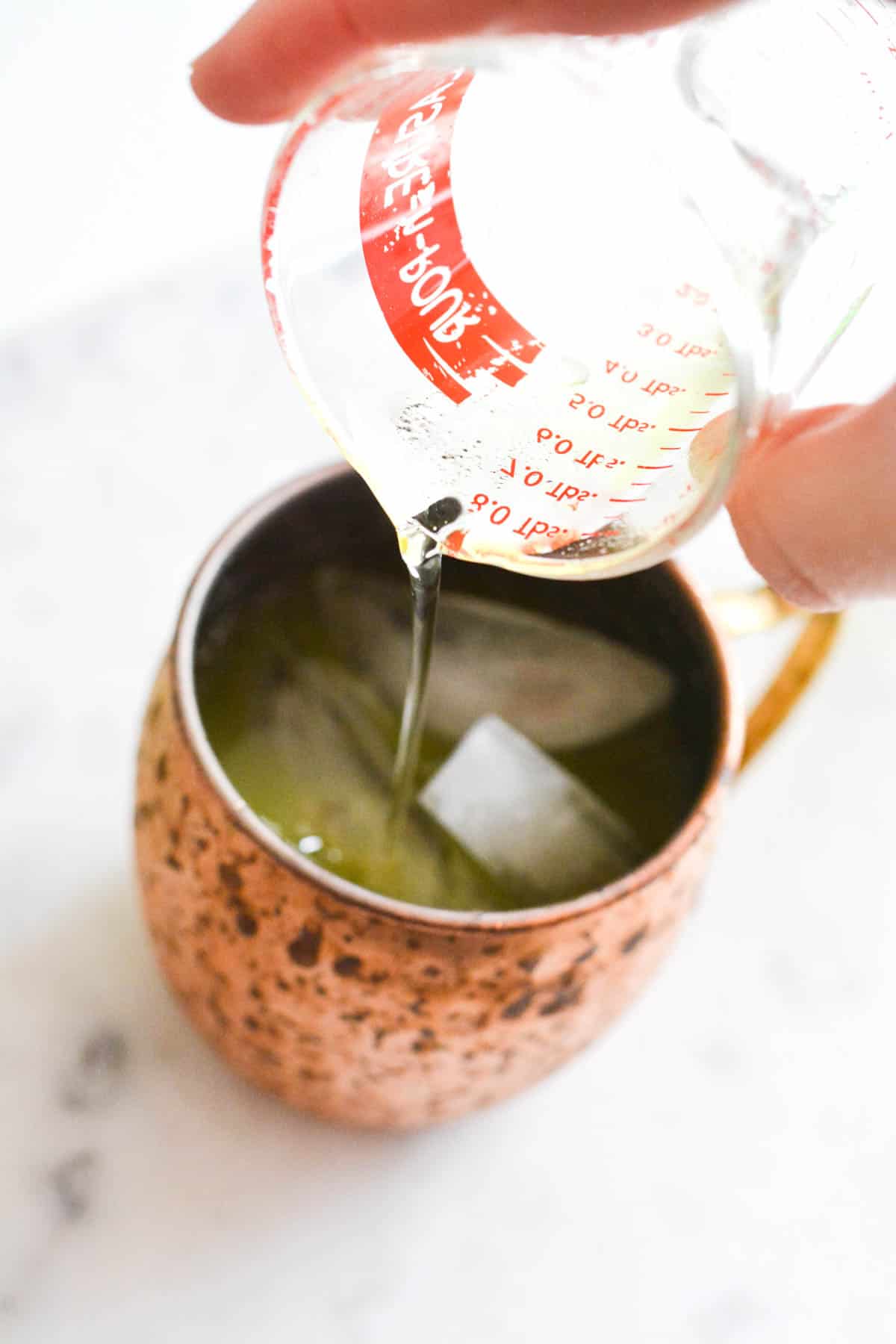 Adding Rose's Lime Juice to a copper Mule mug.