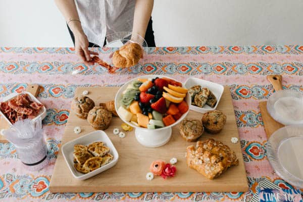 Woman standing next to a table of food for a spring brunch.