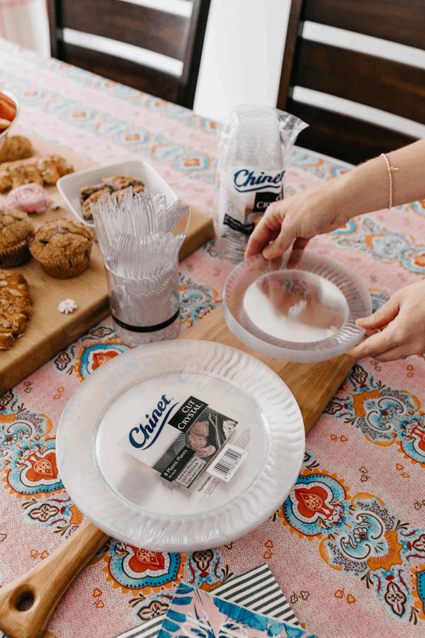 Woman setting a stack of Chinet disposable tableware on the table for a spring brunch party.