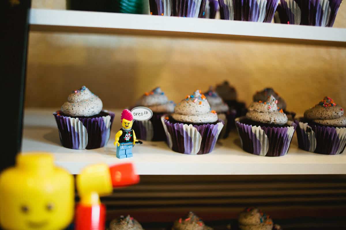 Cupcakes on display for a kids birthday party with a lego dude next to them.