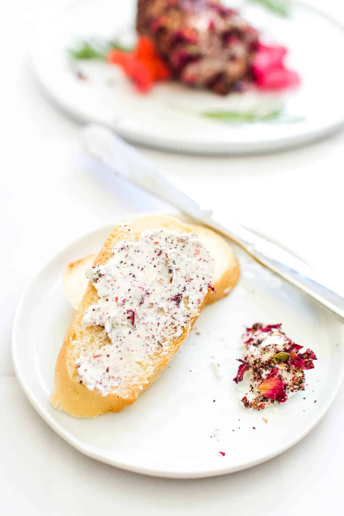A crostini on a plate spread with goat cheese spread.