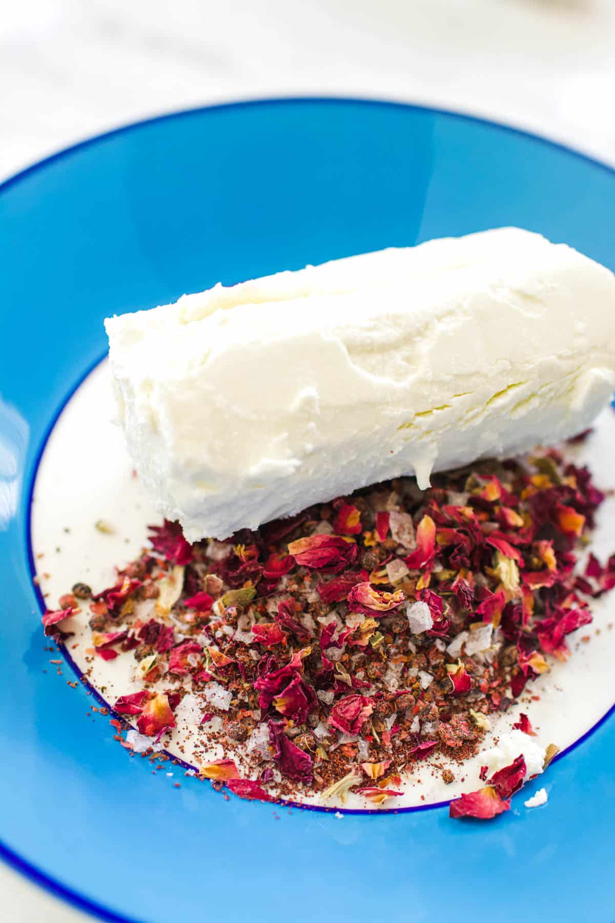 A bowl with spices and a goat cheese log that will coated for an easy appetizer recipe.