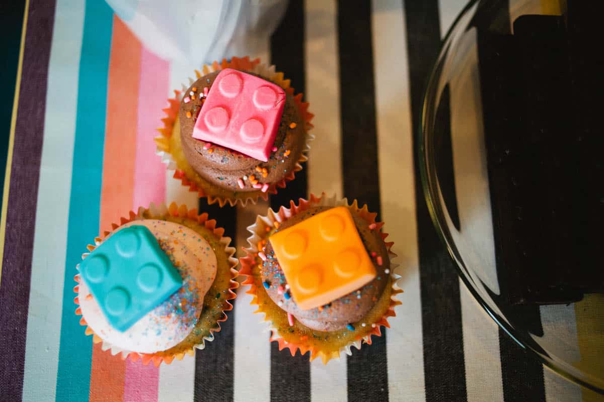 3 cupcakes with a lego candy topping.