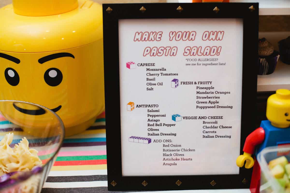 A kids table decoration for a lego party giving the menu and directions for making your own pasta salad