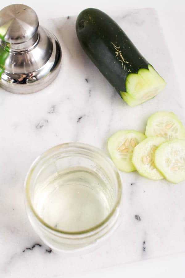 A jar with a homemade cucumber infused vodka to use in a gimlet.