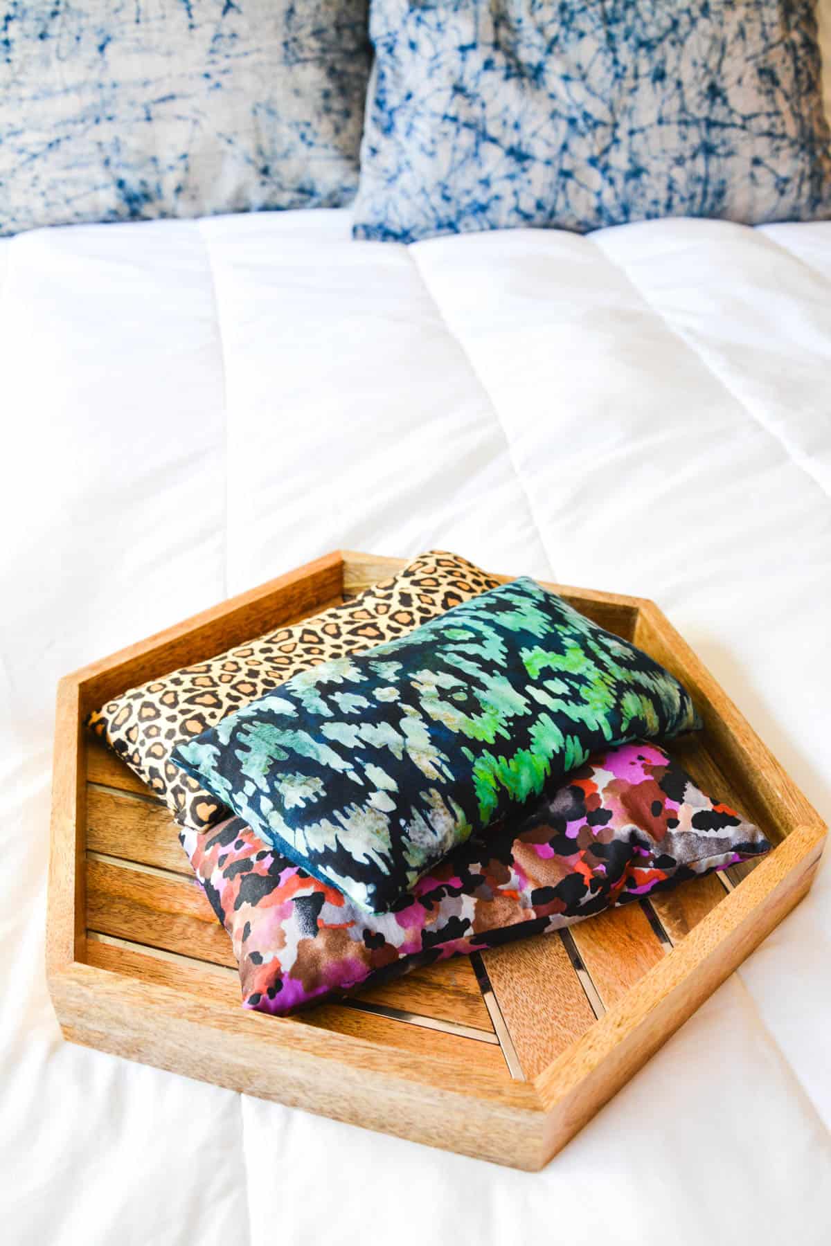 A tray on a bed holding small fabric eye pillows.