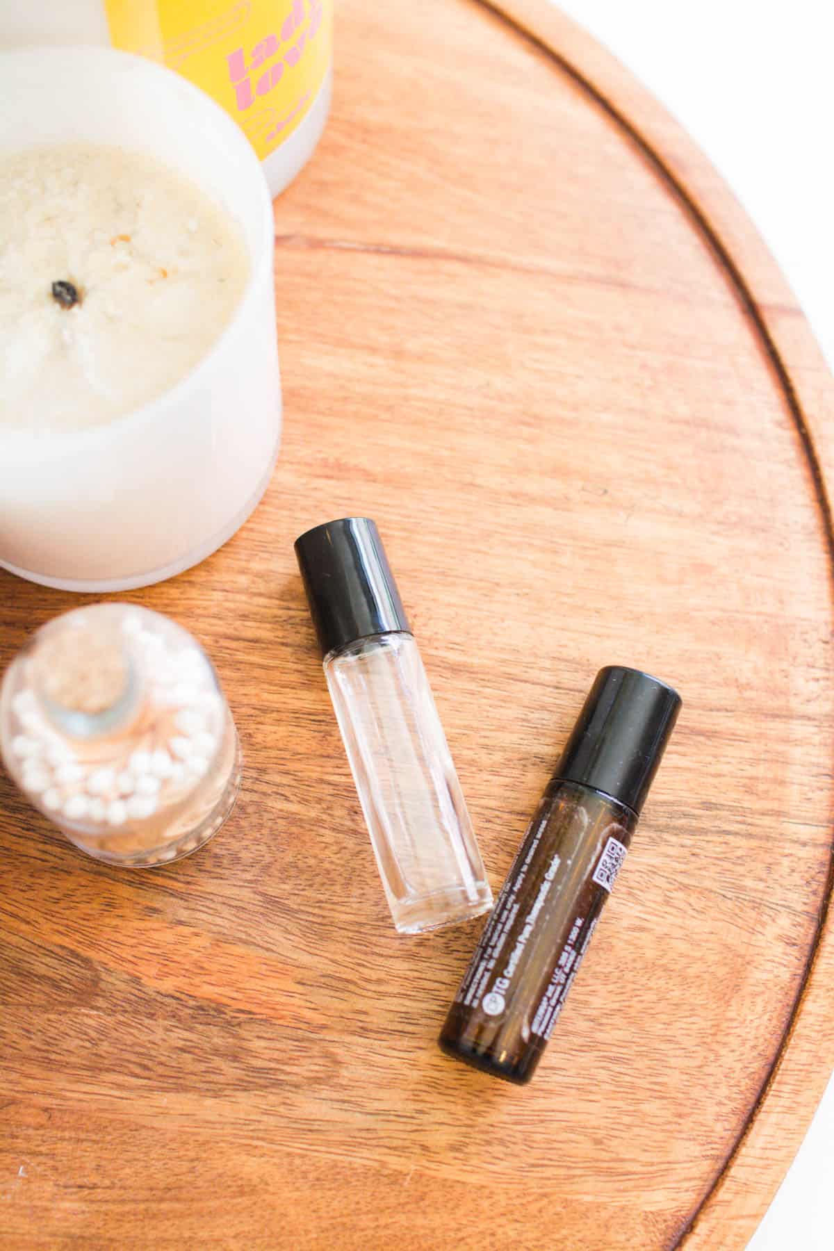 Two glass roller-ball bottles with essential oils on a tray on a table.