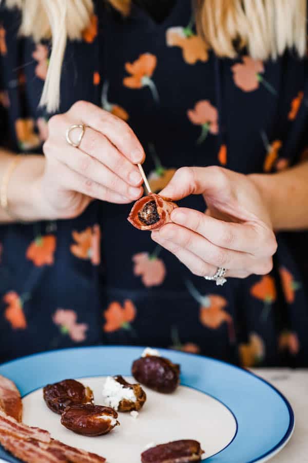Woman adding a toothpick to a date wrapped in bacon.