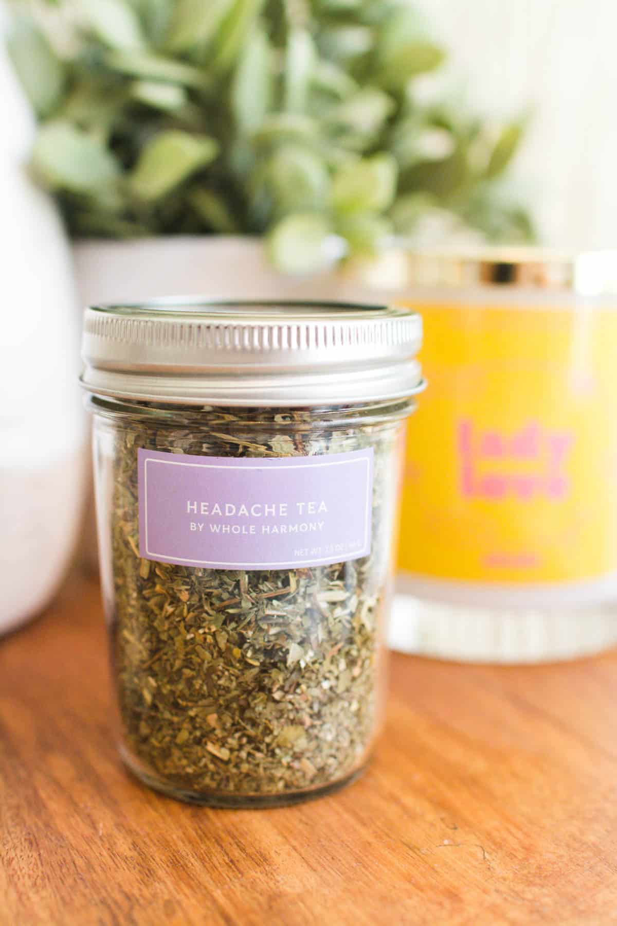 A jar of tea on a table with a purple label.