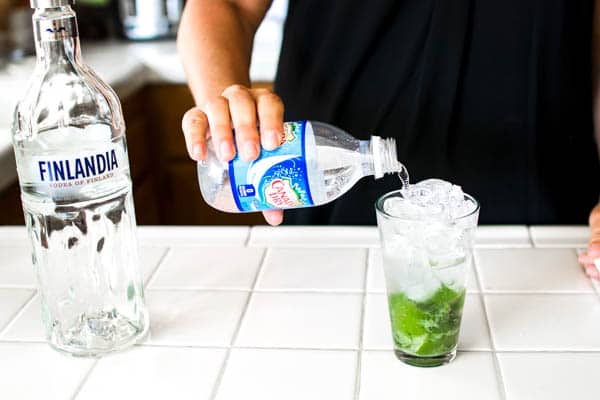 Adding club soda to a mojito cocktail made with vodka. 