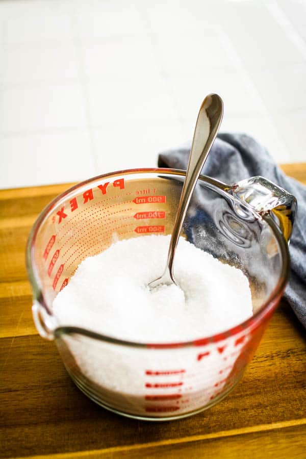 A glass measuring cup with salt and other ingredients with a fork in it. 