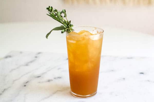 Easy vodka and apple juice cocktail idea in a tall class with an herb garnish.