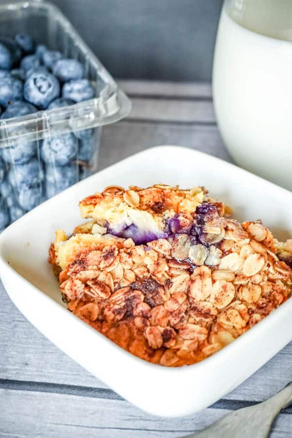 Peach and blueberry dump cake in a serving bowl on a table.