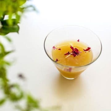 A pear vodka martini topped with edible flowers for garnish.