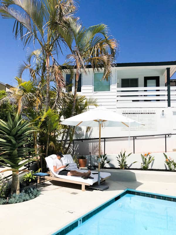 Man sitting on a chase lounge next to a pool in Laguna Beach hotel.