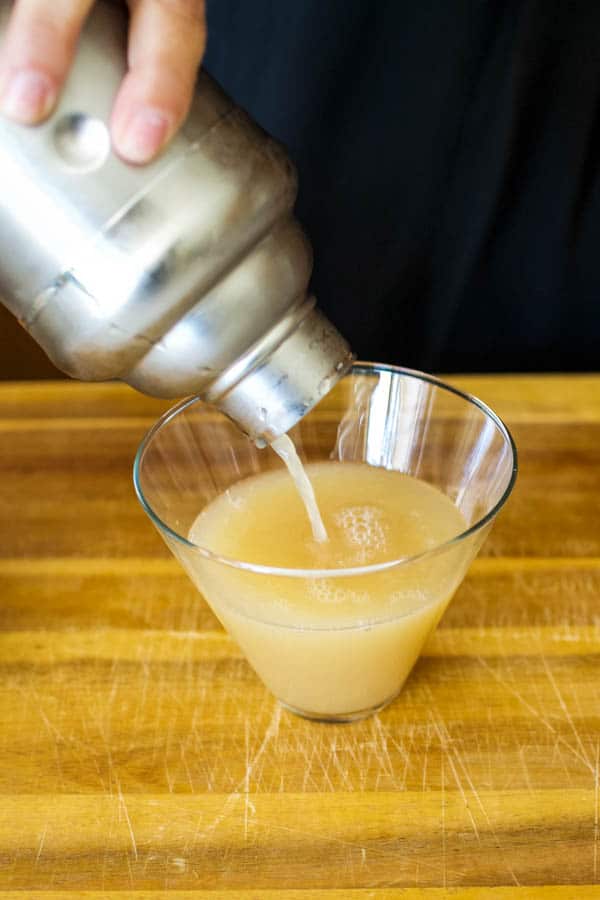 Pouring pear martini into a martini glass.