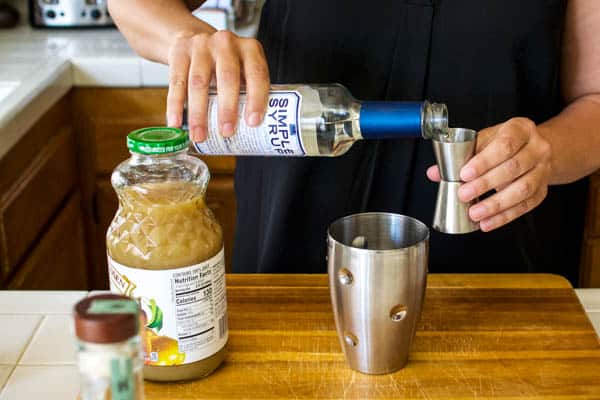 Pouring simple syrup for a cocktail recipe.