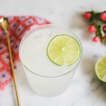 Close up of a skinny margarita in a glass with a lime garnish on a table.