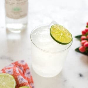 Close up of a skinny margarita on a cutting board with a fresh lime slice for a garnish.