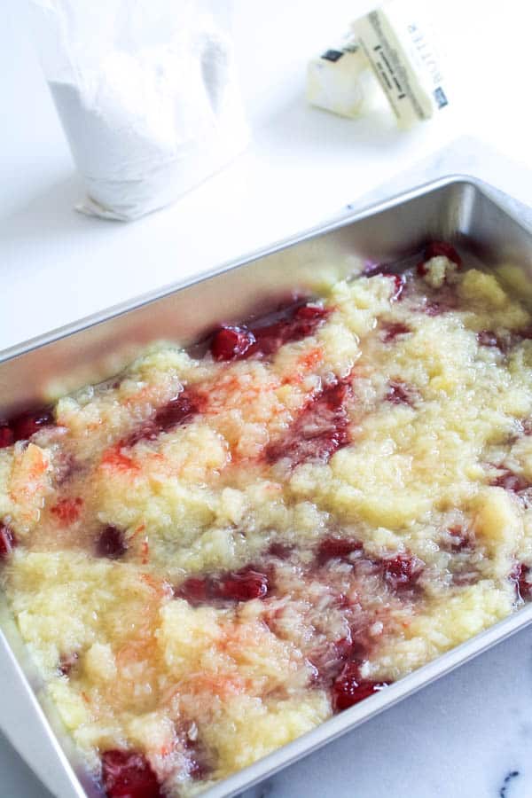 Strawberry pie filling and crushed pineapple in a cake pan for a dump cake.