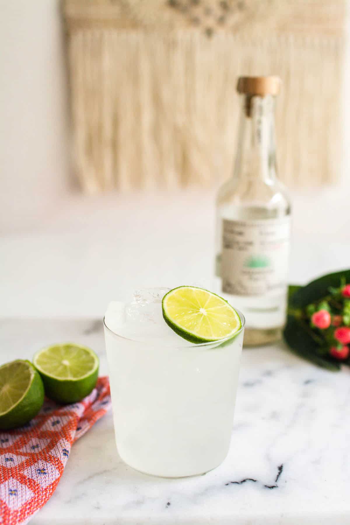 A skinny margarita on a marble cutting board with a bottle of tequila in the background.