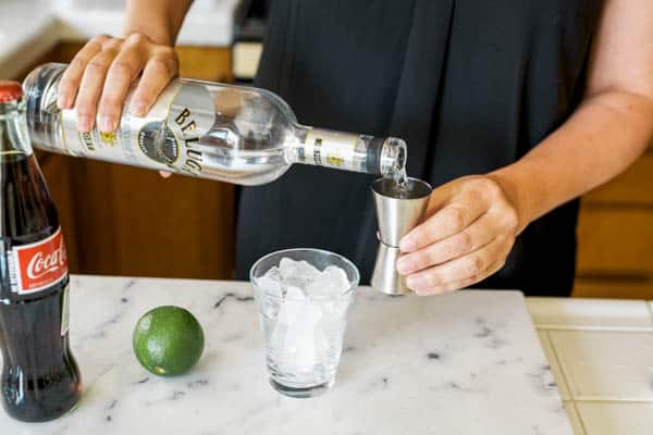 woman pouring vodka in a jigger at a counter.