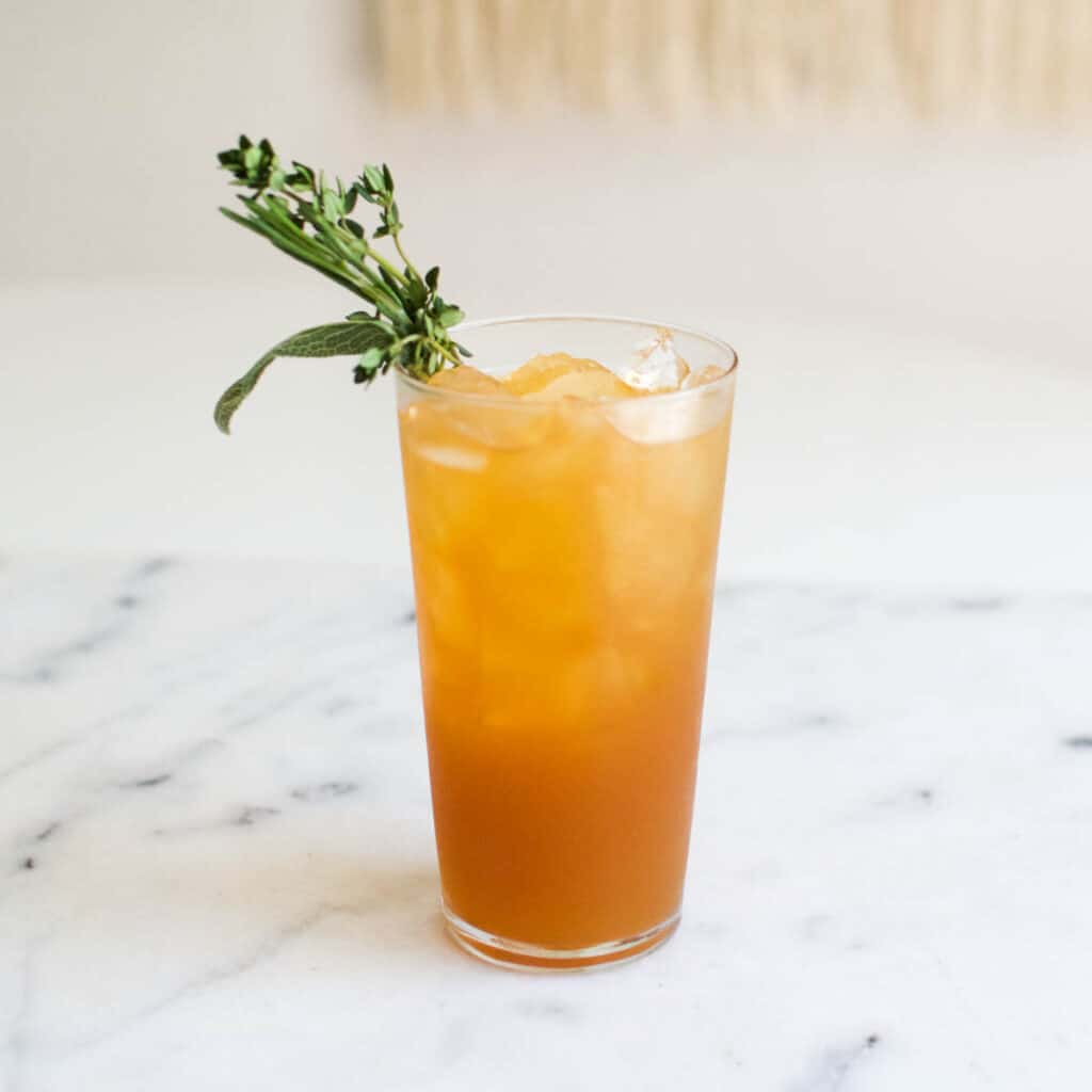 Vodka and Apple Juice over ice in a high ball glass on a table.