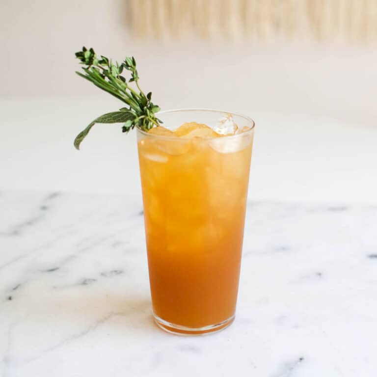 Vodka and Apple Juice over ice in a high ball glass on a table.