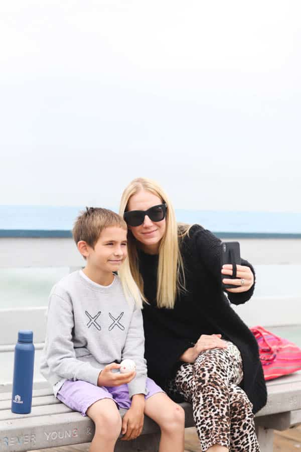 mom and son taking a selfie sitting on a bench on the san clemente pier.