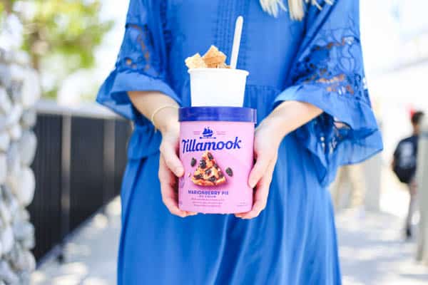 woman holding a gallon of Tillamook ice cream with a sundae on top.