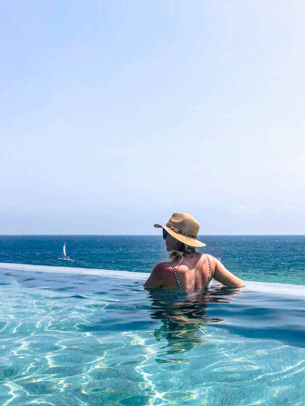 Woman in infinity pool with ocean behind her.