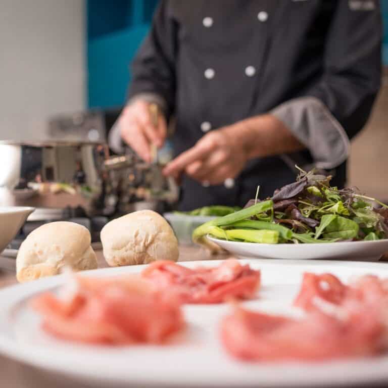Food on a plates on a counter with a chef working in the background.