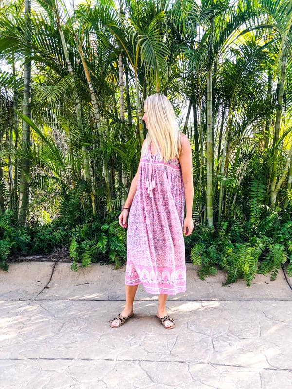 women in pink hippie dress standing in front of palm trees