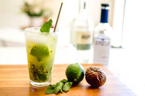 A finished passion fruit vodka mojito on a cutting board with vodka and simple syrup in the background