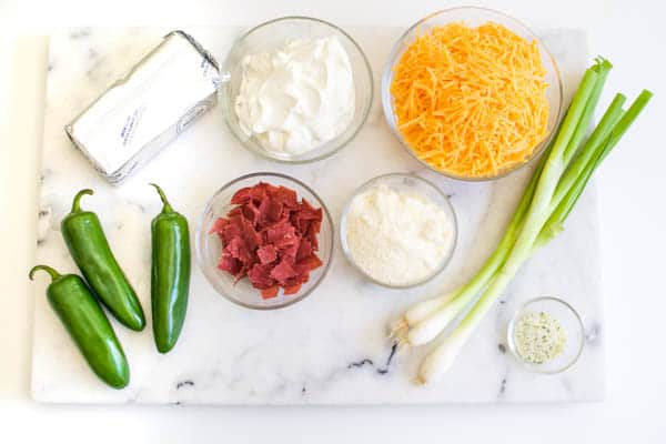 Ingredients to make a Jalapeno Popper Dip laying on a marble cutting board.