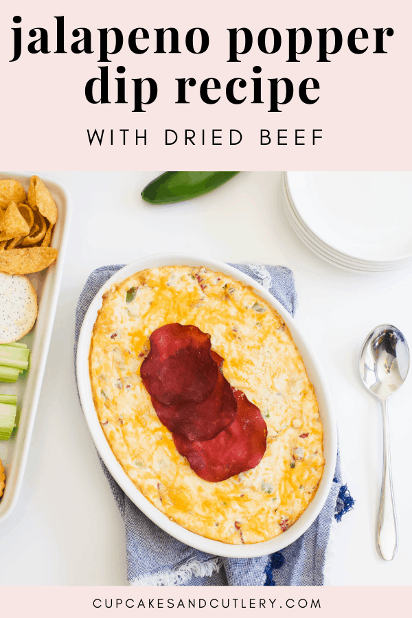 Jalapeno Popper Dip on a table with crackers and plates around it and a text overlay