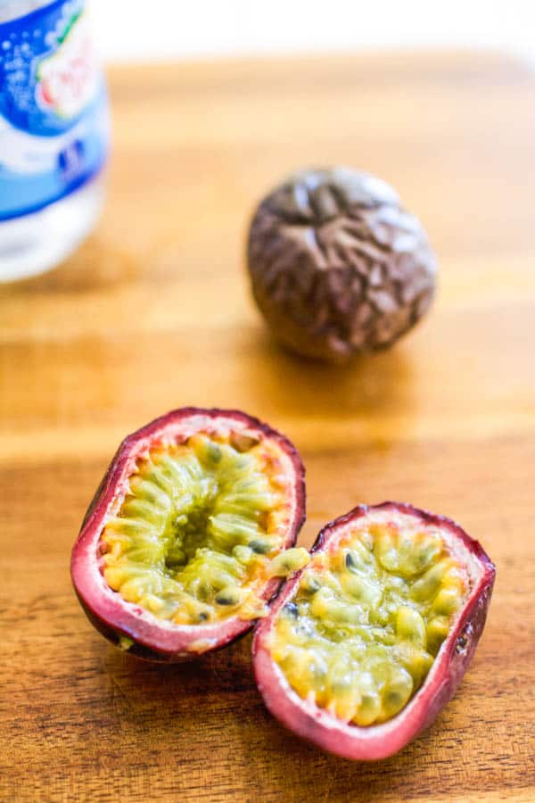 A passion fruit cut and laying on a wooden cutting board