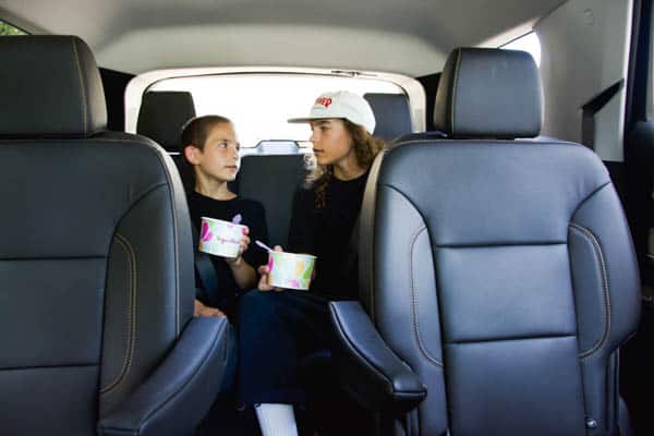 Two boys in the back seat of a Chevy Traverse eating Yogurtland