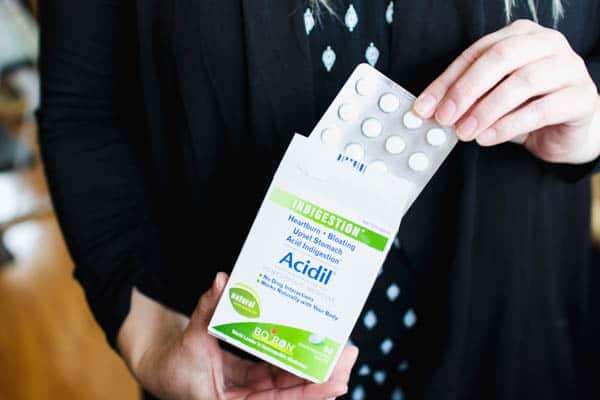 A box of Boiron Acidil held by a women.