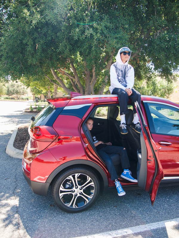 Kids sitting in and on a Chevy Bolt.