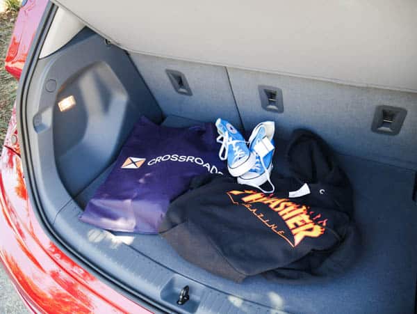 Crossroads Trading bag next to Thrasher hoodie and blue Converse sneakers in the back of a Chevy Bolt.