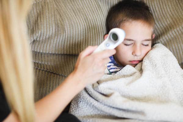 mom taking a kid's temperature on forehead